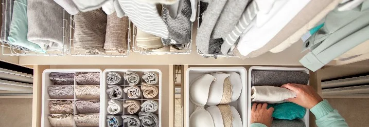 Person räumt Kleidung in einem Kleiderschrank ein